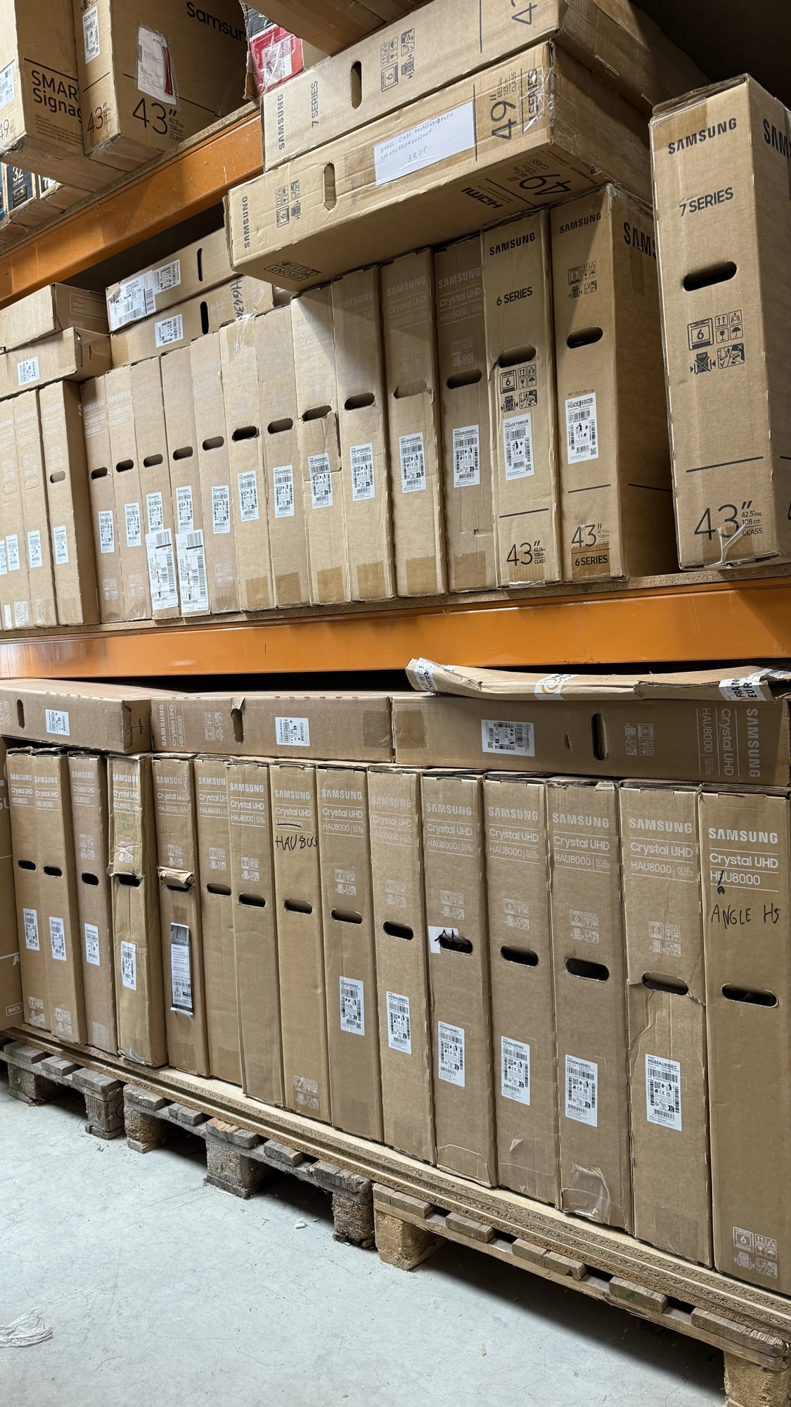 Téléviseurs et équipements emballés, regroupés sur les rayonnages du stock.